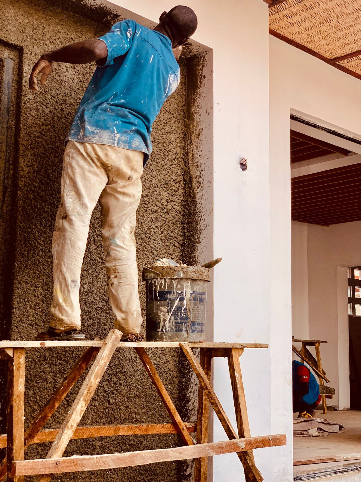 Artisan en plein enduit sur un mur, les deux mains prises, qui ne peut pas décrocher le téléphone