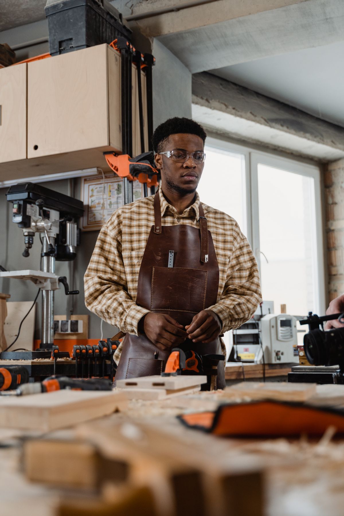 Artisan menuisier dans son atelier, lunettes de protection, concentré sur son établi