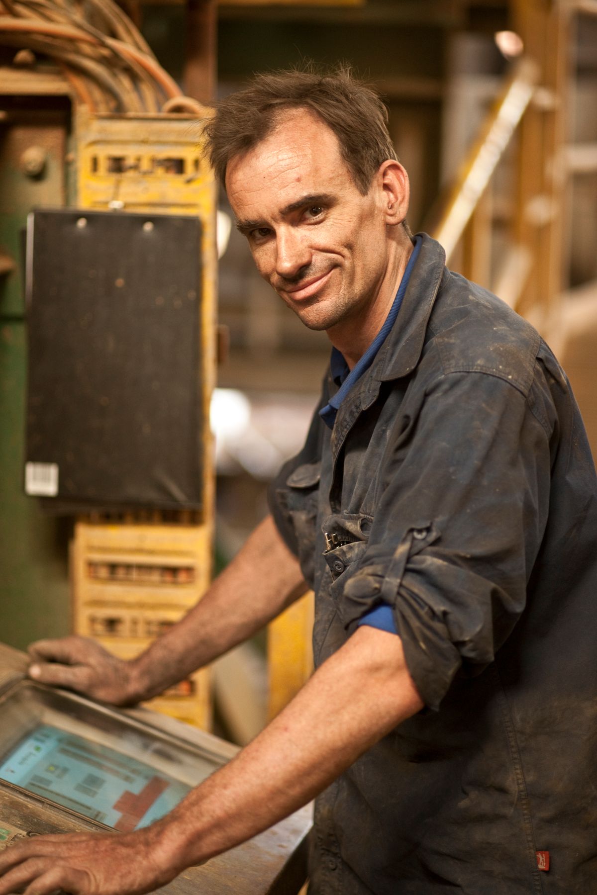 Artisan souriant devant l'écran de son tableau de bord dans son atelier